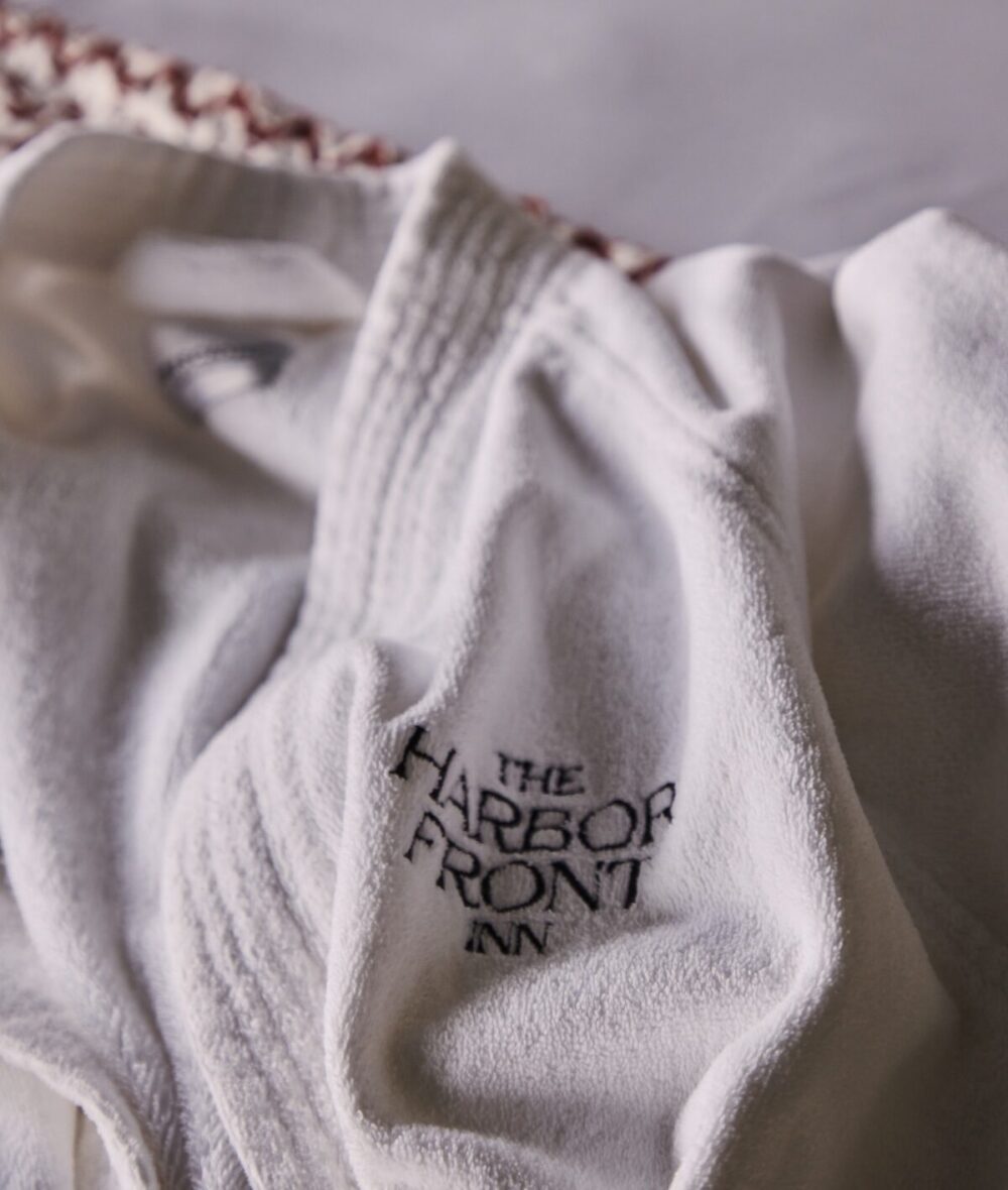 A plush, white bathrobe with The Harbor Front Inn logo.