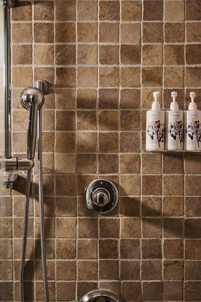 A tiled shower with Red Flower bath products.