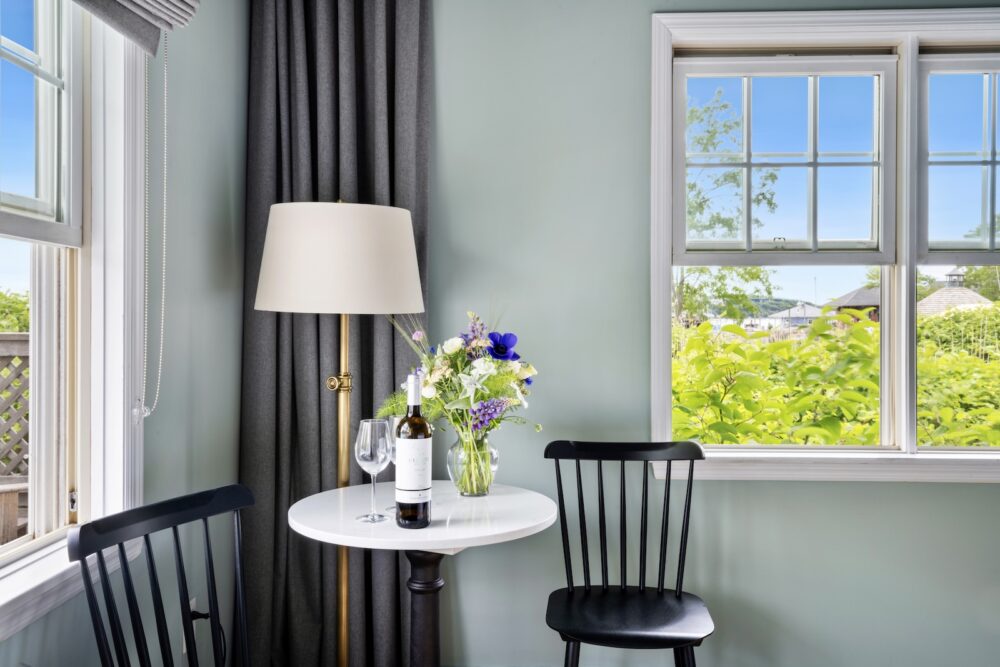 A small table with two chairs and a bottle of wine in the corner of Junior Suite at Harbor Front Inn.