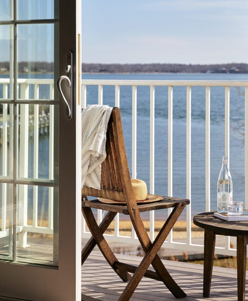 A wooden chair on a patio, with a blanket and table.