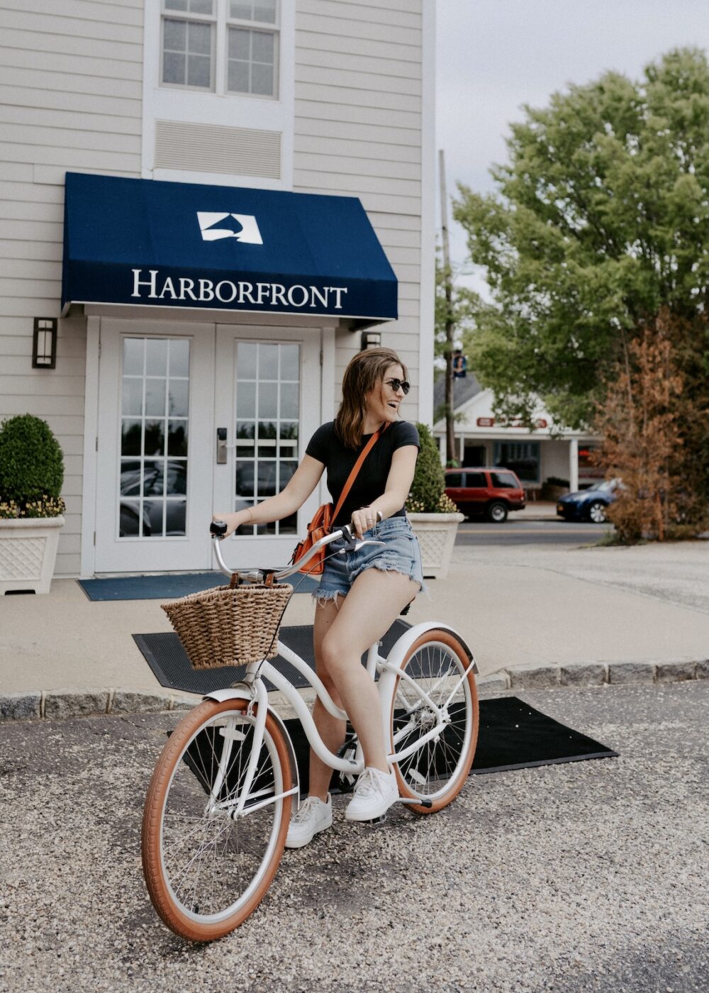 A woman riding a cruiser bike outside of the The Harbor Front Inn in Greenport, NY.