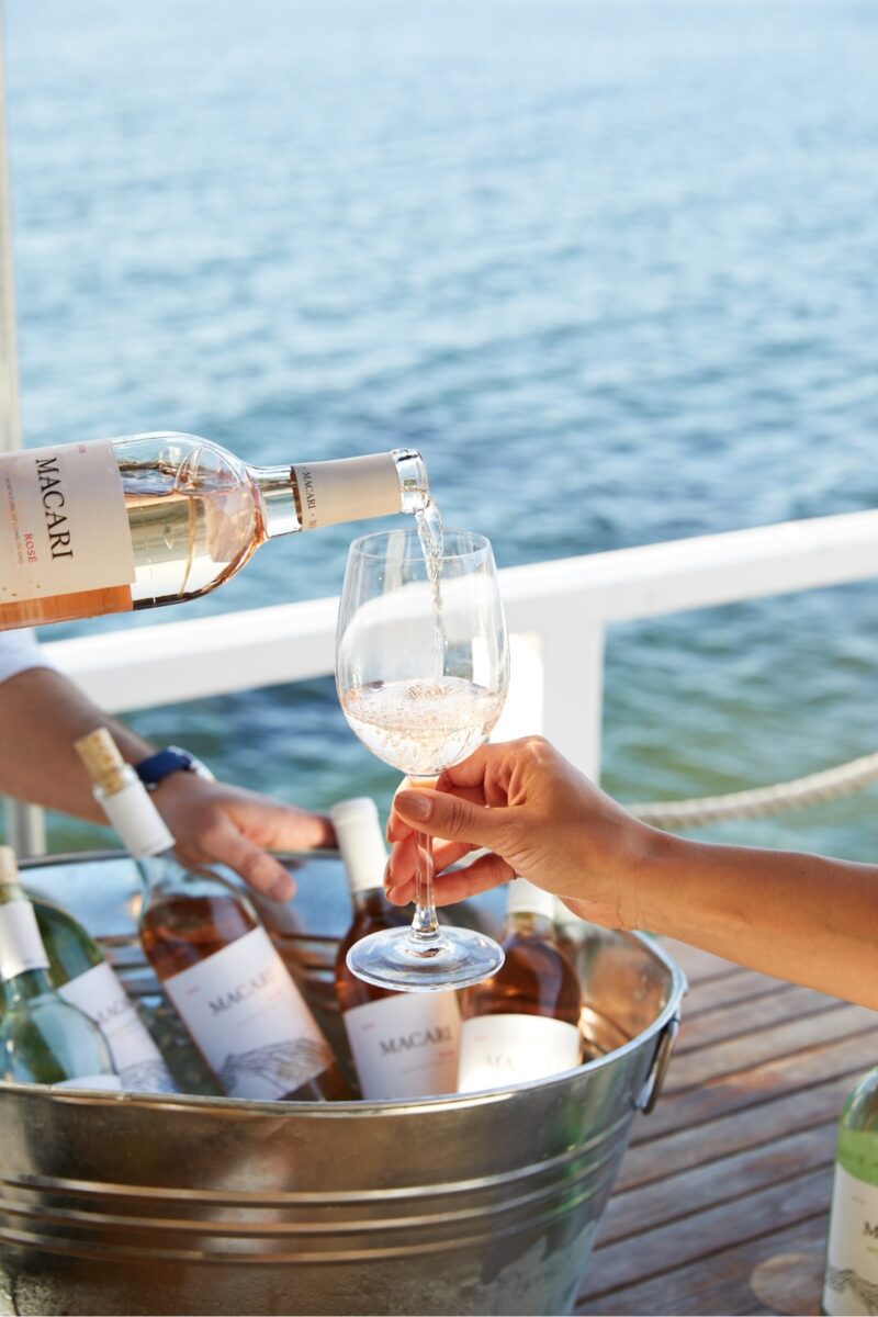 Pouring rosé wine into a glass. A bucket full of various wines.