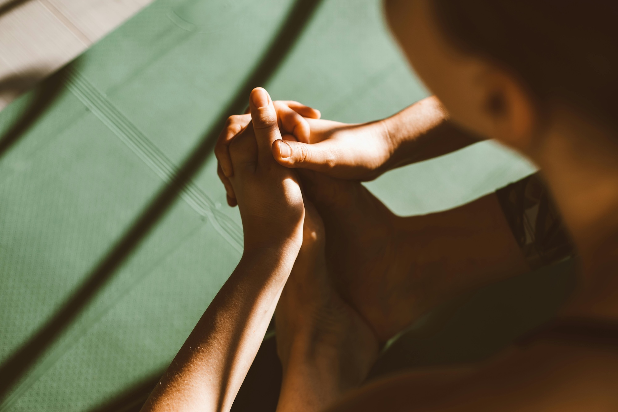 A woman practicing yoga on a green mat.