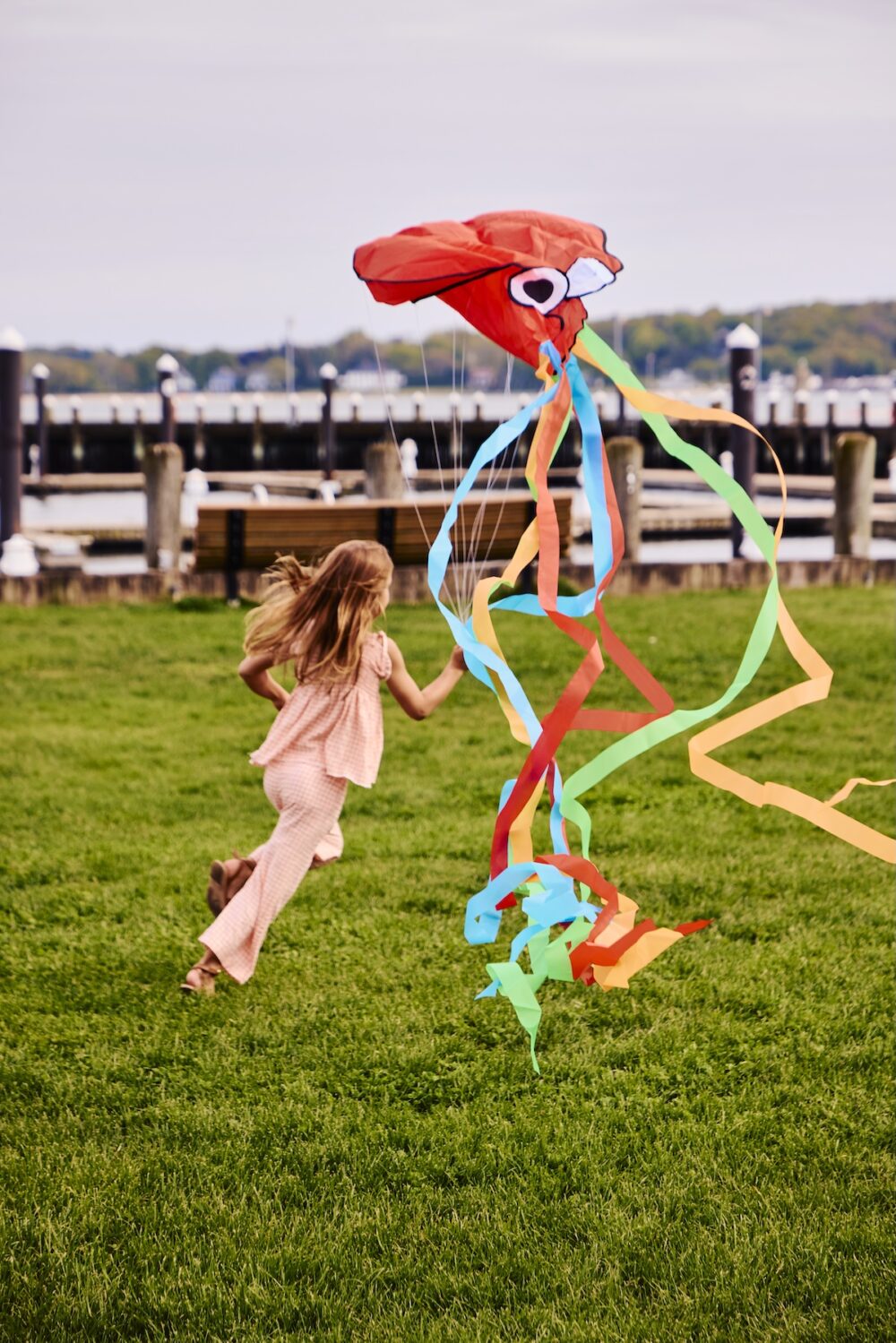 A young girl playing with a kite in the park.