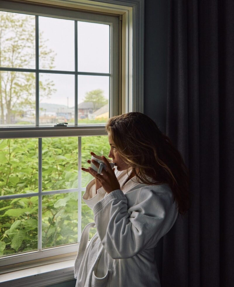 A woman in a Harbor Front Inn bathrobe holding a cup of coffee.