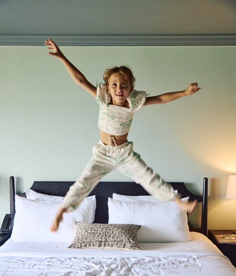 A little girl jumping on a bed at Harbor Front Inn.
