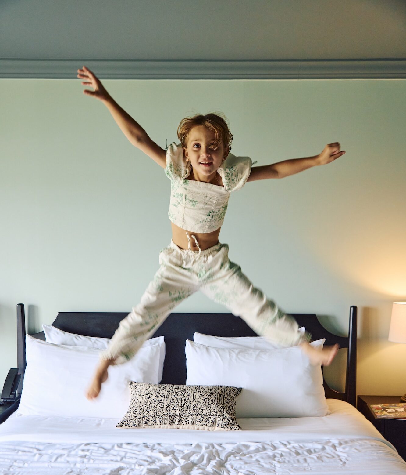 A little girl jumping on a bed at Harbor Front Inn.