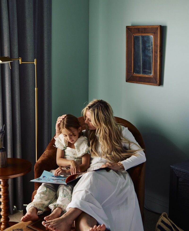 A mother and daughter reading in a guest bedroom.