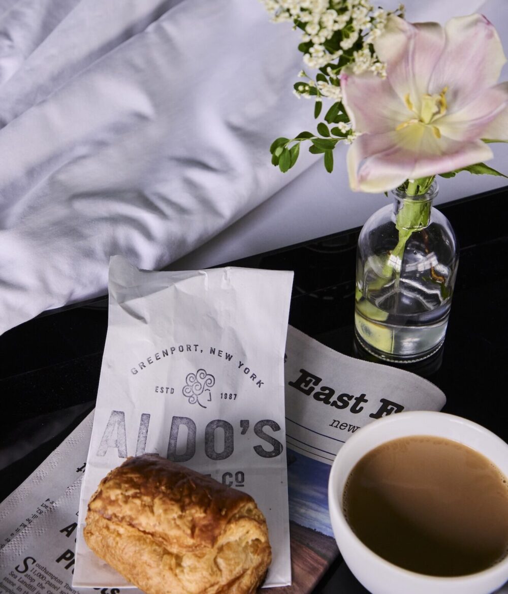 A pastry and cup of coffee next to a guest bedroom.