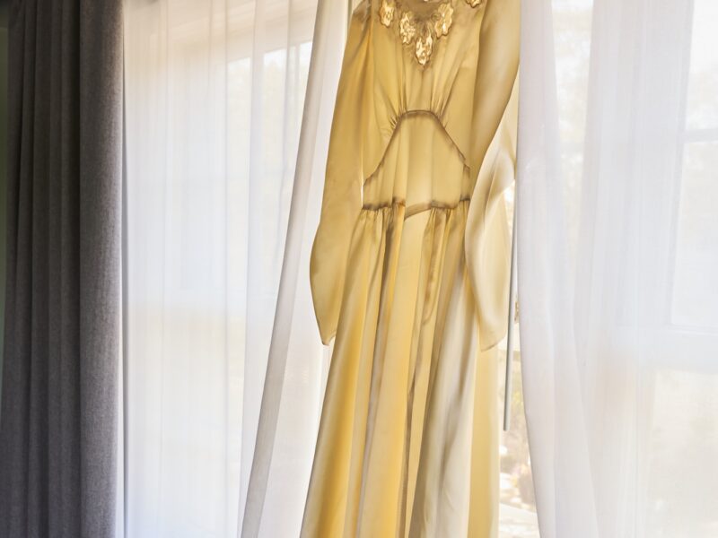 A vintage wedding dress hanging in the window in a suite at The Harbor Front Inn.