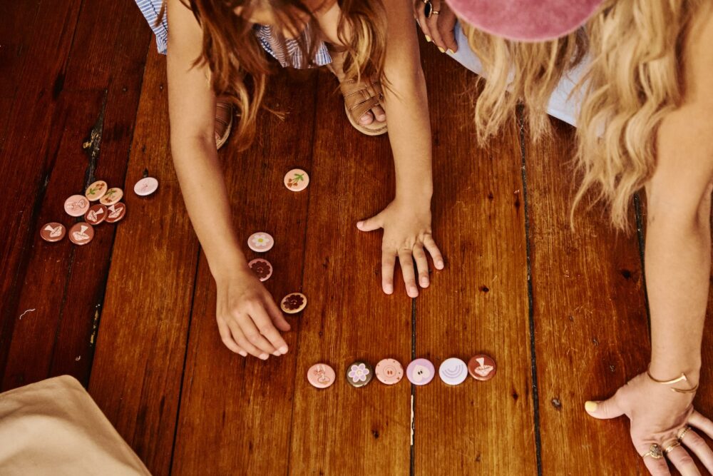 A small child looking at buttons with her mom.