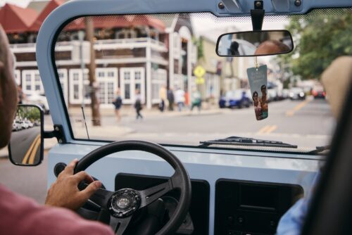 A couple driving a Moke through downtown Greenport, NY.