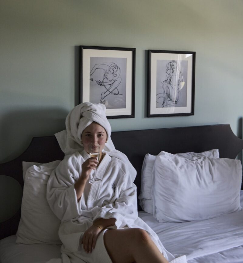 A woman in a bathrobe having champagne.